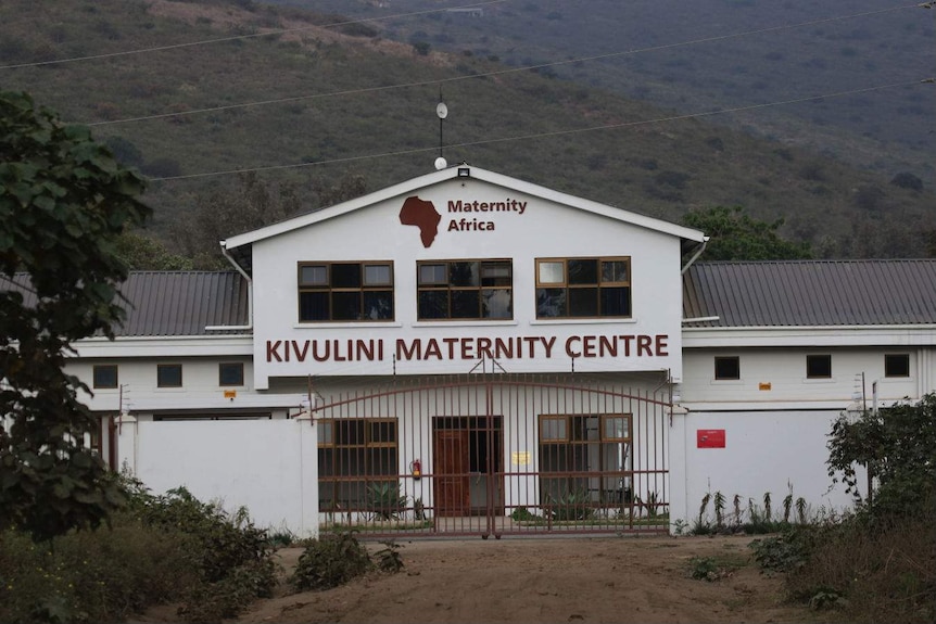 A white maternity hospital against a backdrop of hills and scrub.