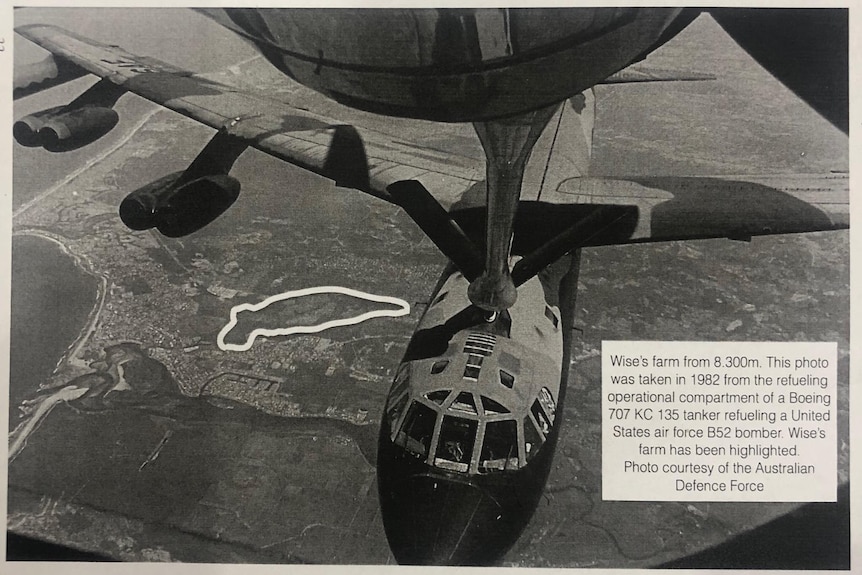 Looking down over a bomber with a white line outlining a farm below.