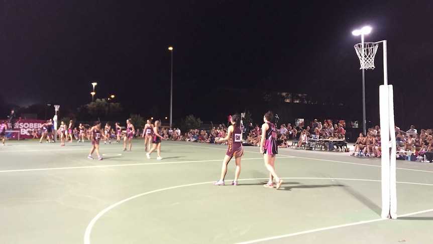 Netball players on a court at night