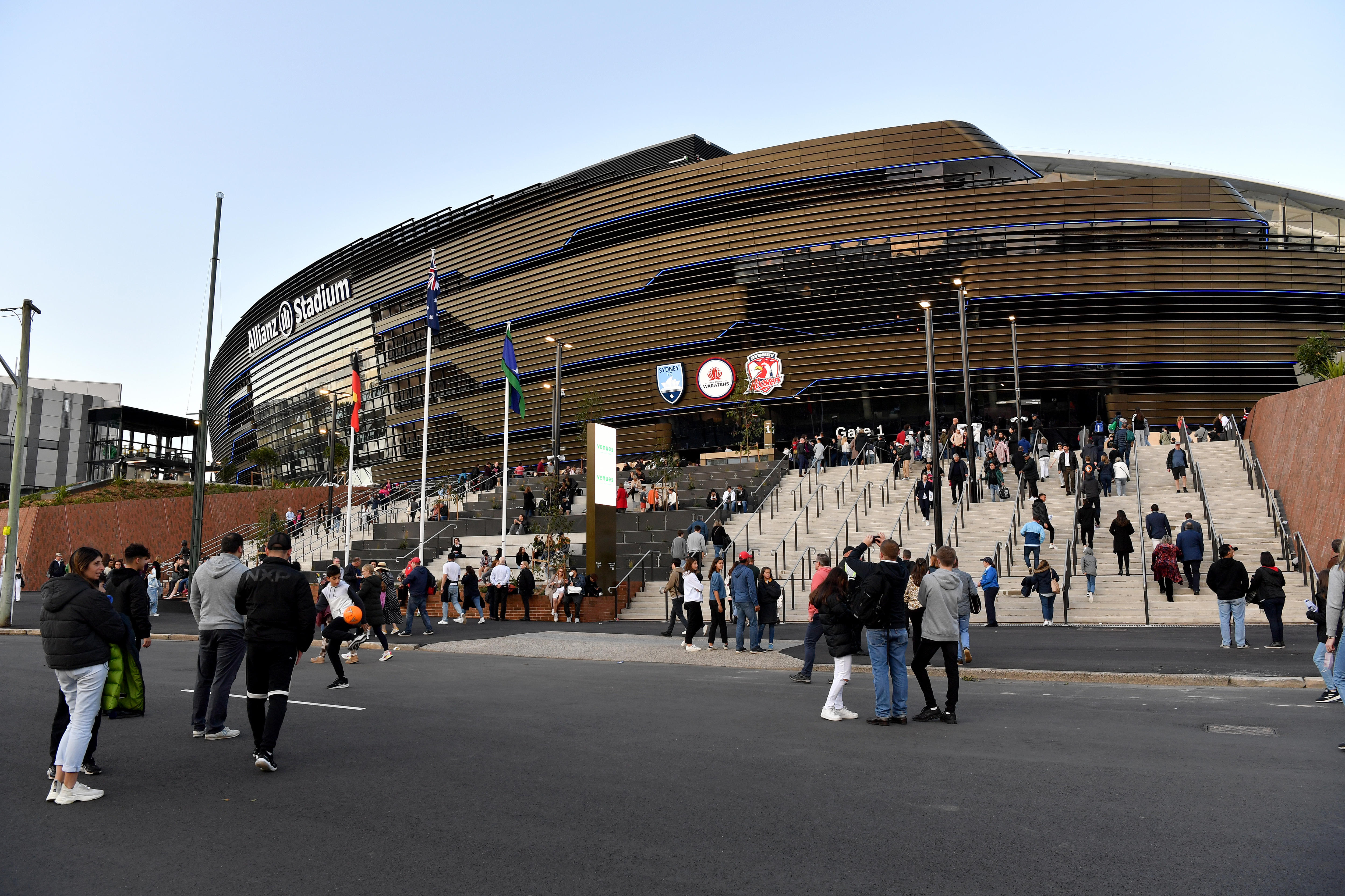 People walk up the stairs toward a shiny new stadium
