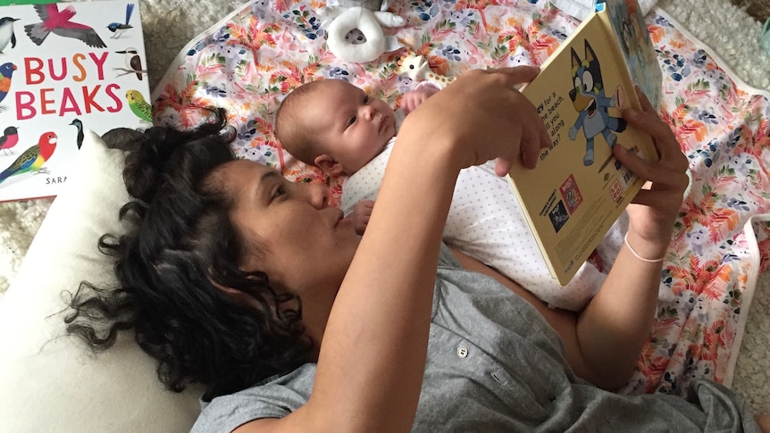 Alice Matthews reading children's book to a small baby, both lying down