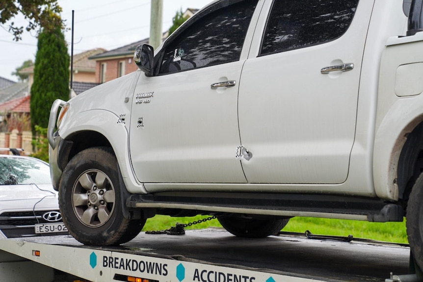 A ute with bullet holes being towed away