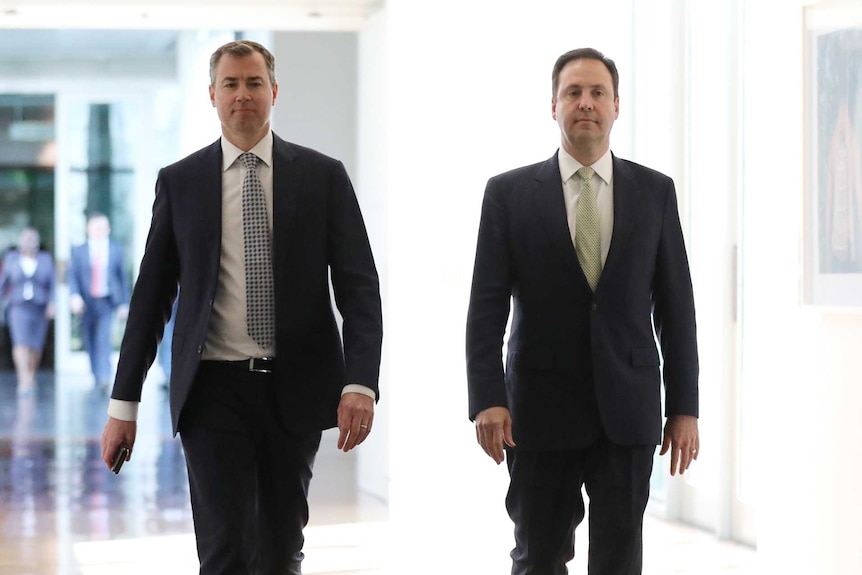 Mr Keenan and Mr Ciobo are both mid stride. Mr Keenan's jacket is open, while Mr Ciobo is buttoned up.