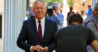 A smiling Colin Barnett walks towards the camera with a TV cameraman in front of him.