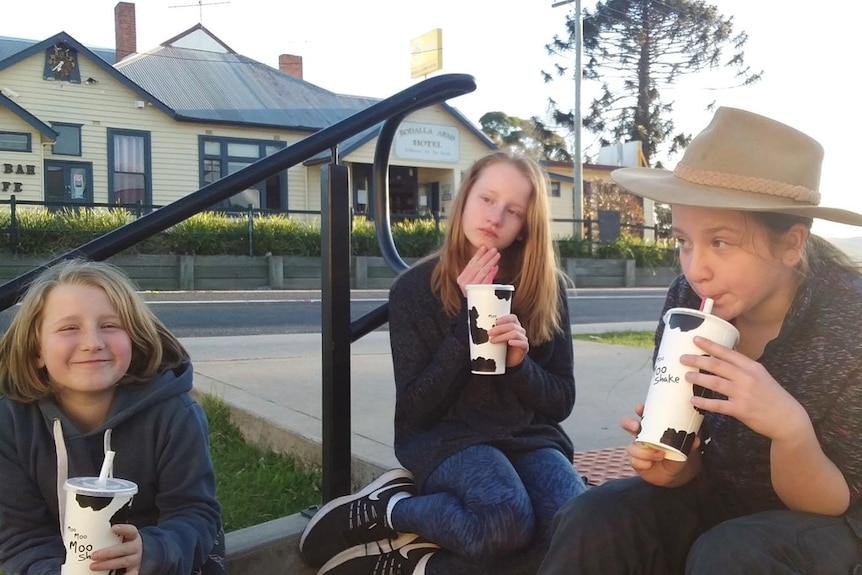 Three teenage girls drink a milkshake.