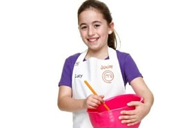 A girl looks at the camera while holding a mixing bowl.