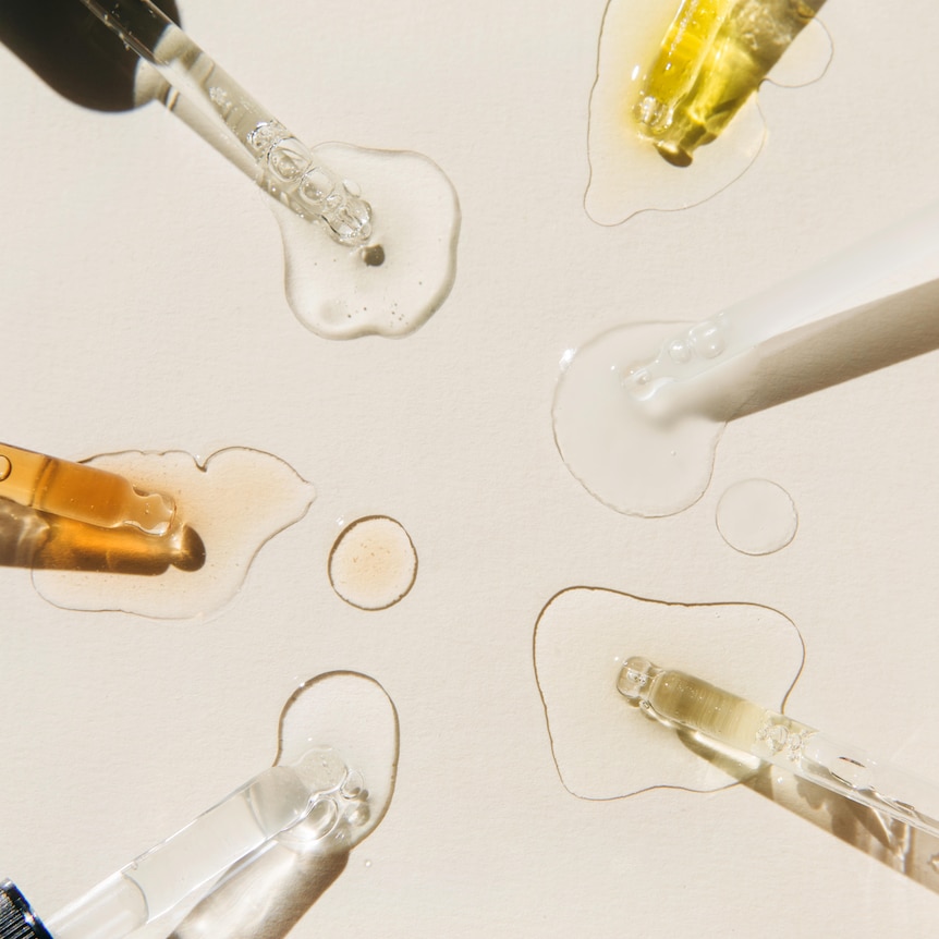 Serum droppers in a circle facing inwards on beige background.