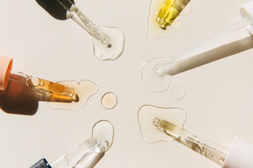 Serum droppers in a circle facing inwards on beige background.