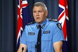 A med shot of WA Police Deputy Commissioner Col Blanch speaking at a podium during a media conference.