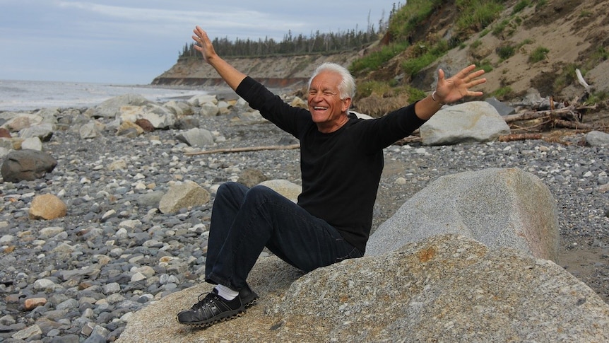 happy middle-aged man on a beach, raising his hands