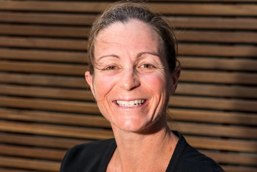  A woman smiles for a portrait against a wooden background