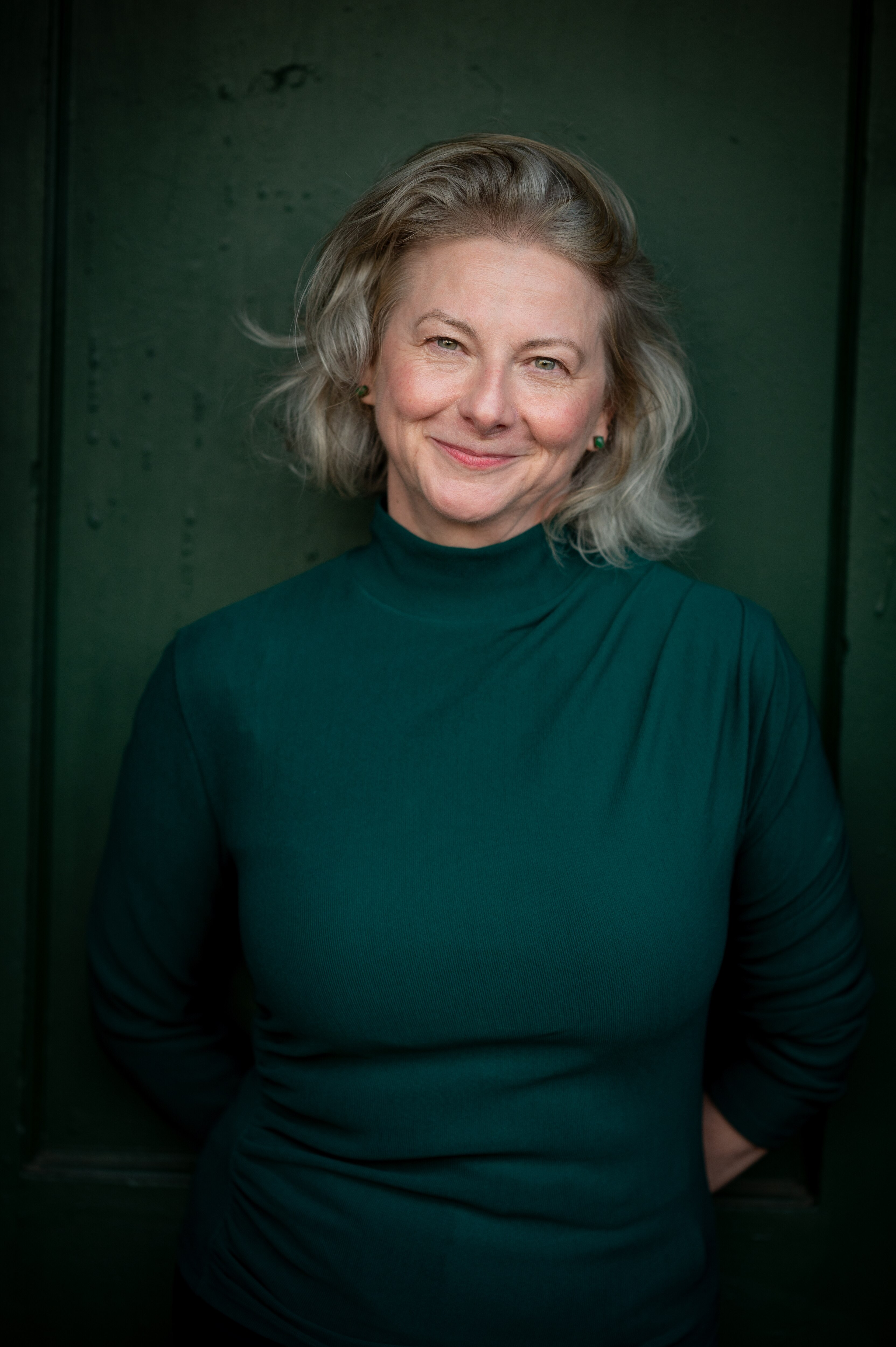 Author headshot, toni wears a somber green dress.