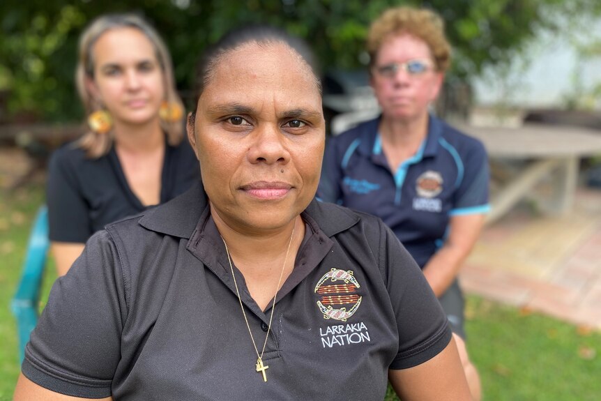 Portrait of a woman Lulu Coombes sitting with her Larrakia Nation colleagues in Darwin