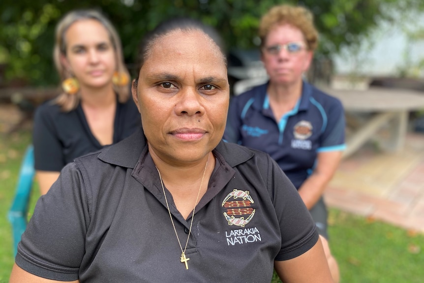 Portrait of a woman Lulu Coombes sitting with her Larrakia Nation colleagues in Darwin