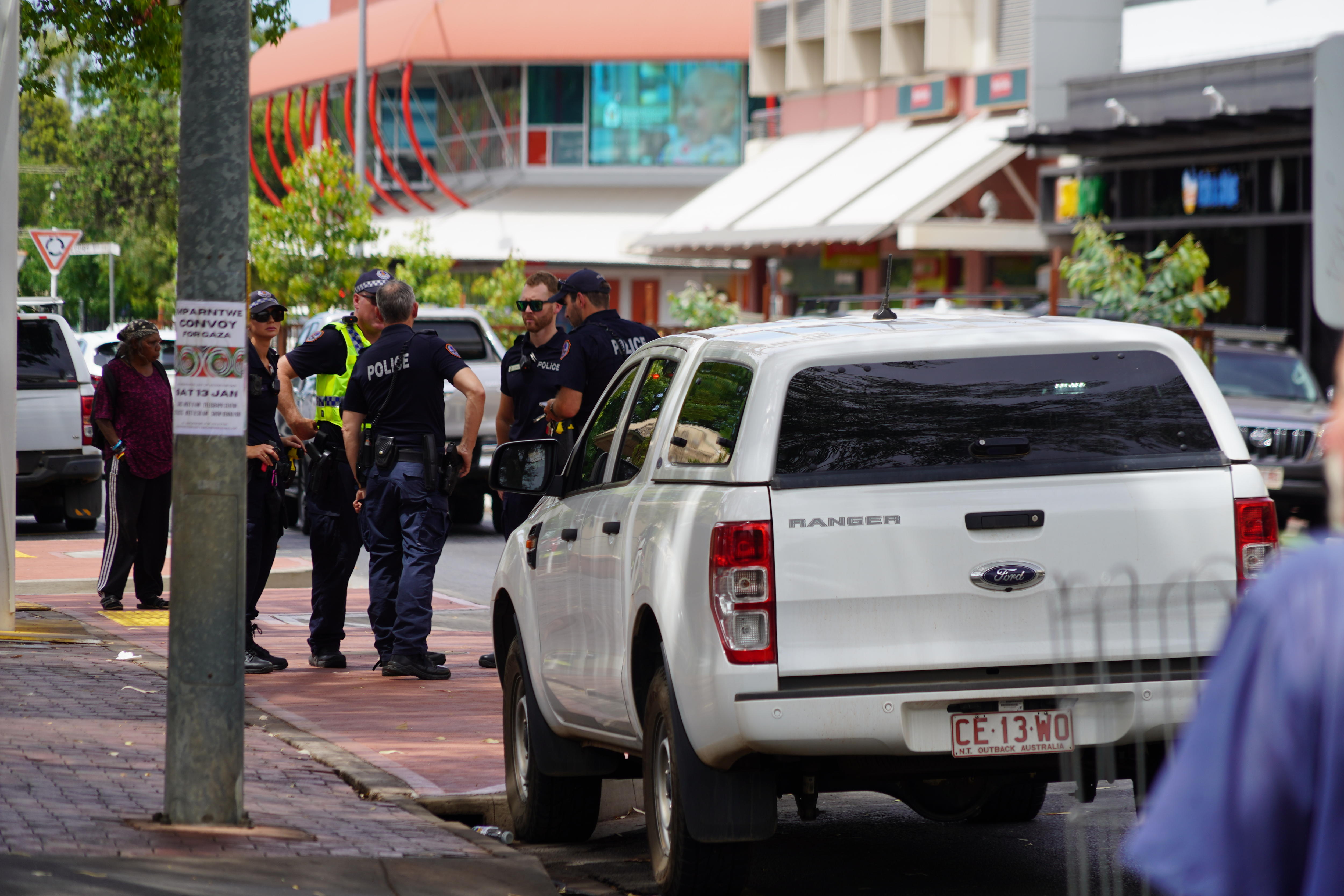  A group of police wearing navy stand on a street and talk. They look serious.