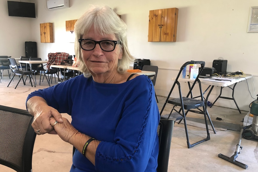 A woman with grey hair and glasses sitting at a table.