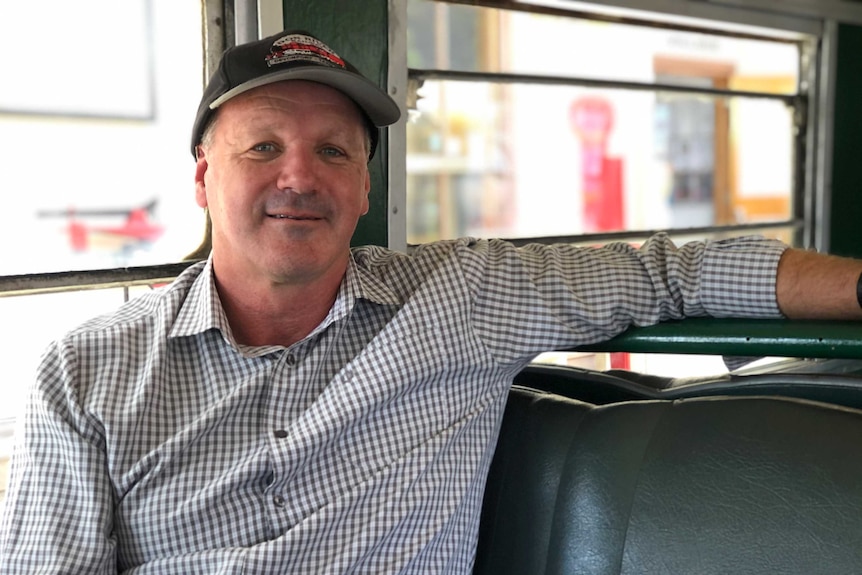 Man sitting in a train carriage looks at the camera