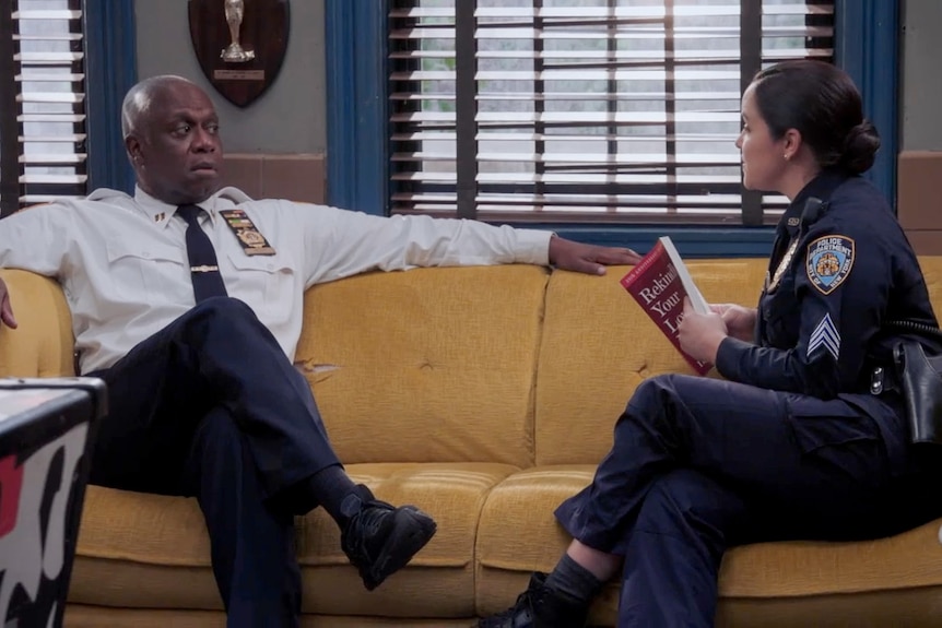 Dwóch policjantów, mężczyzna i kobieta, siedzą na kanapie i rozmawiają