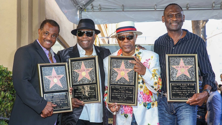 Robert "Kool" Bell, from left, Ronald "Khalis" Bell, Dennis "DT" Thomas and George Brown hold up their Hollywood stars.