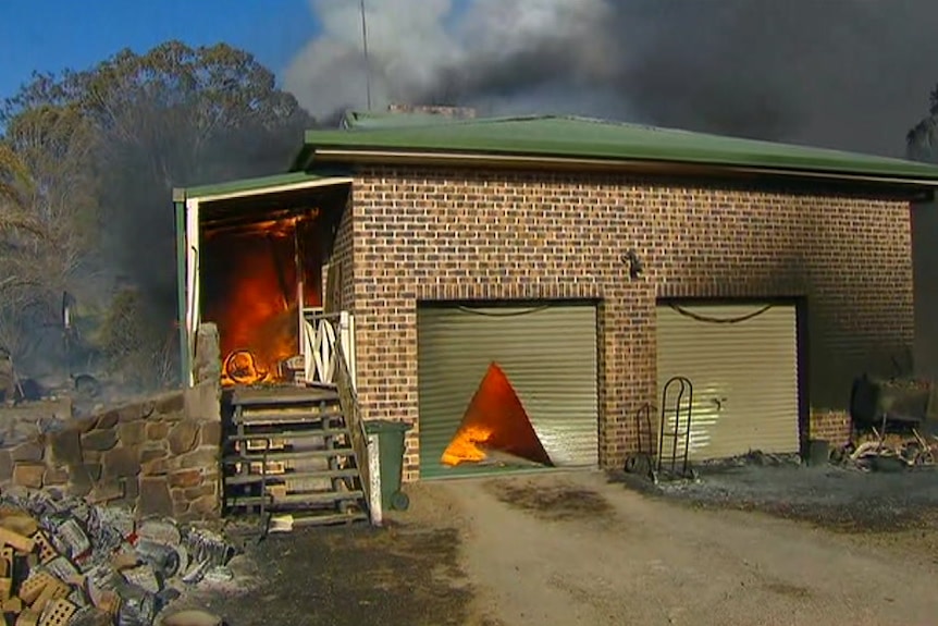 Fire burns at the front door and garage of a house.