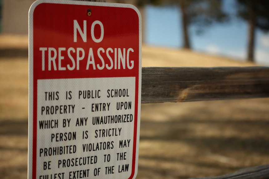 A sign reads 'No Trespassing: This is a public school property'.