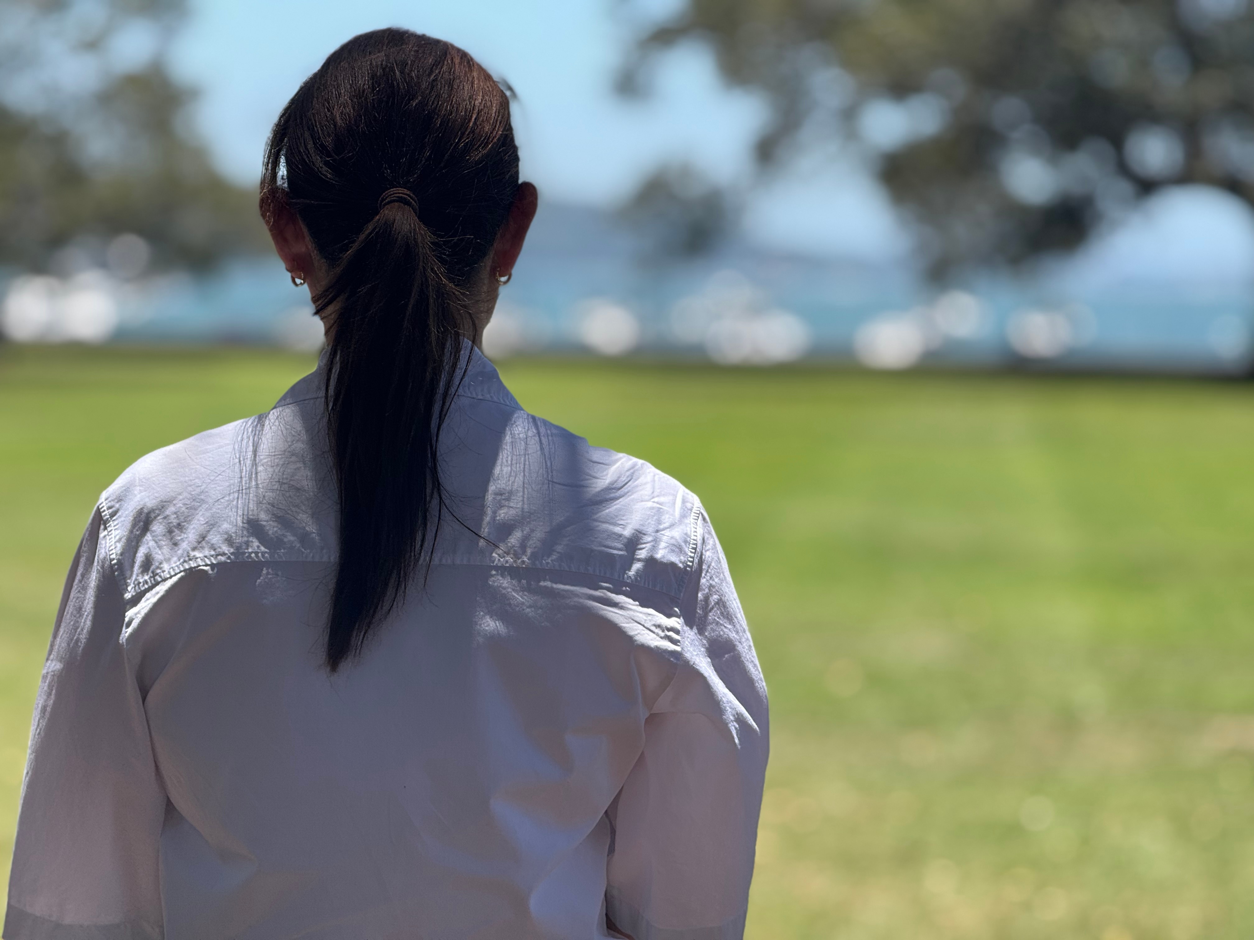 Una mujer con el pelo recogido en una cola de caballo aparta la mirada de la cámara.
