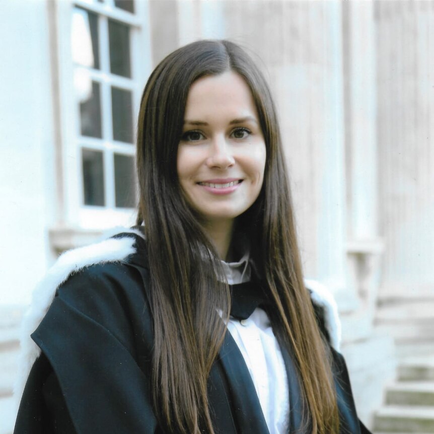 A woman in a university robe smiles