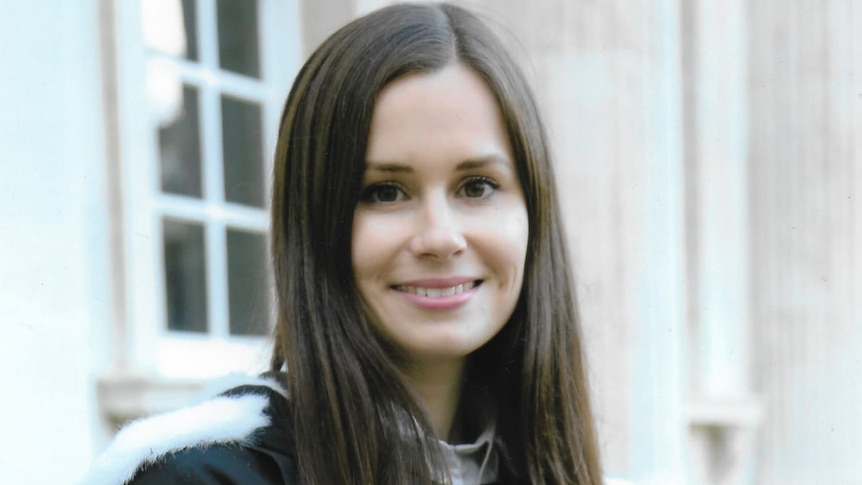 A woman in a university robe smiles