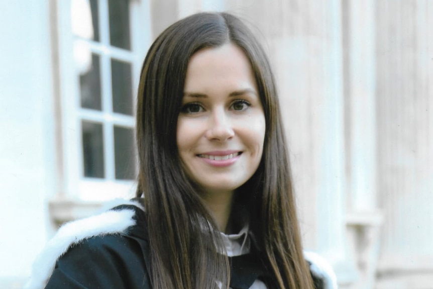 A woman in a university robe smiles