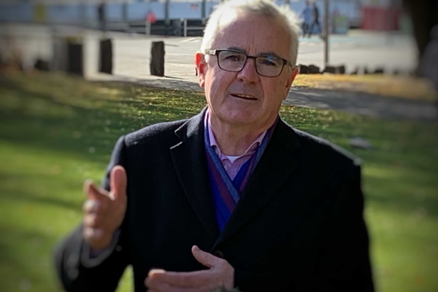 Andrew Wilkie gesticulates as he talks in a park.
