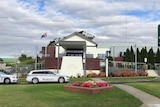 An exterior shot of a country town police station with police cars parked out the front.
