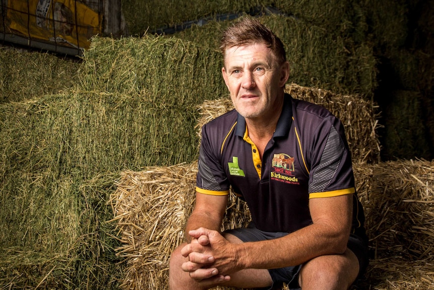 Craig Kirkwood sits on hay bales.
