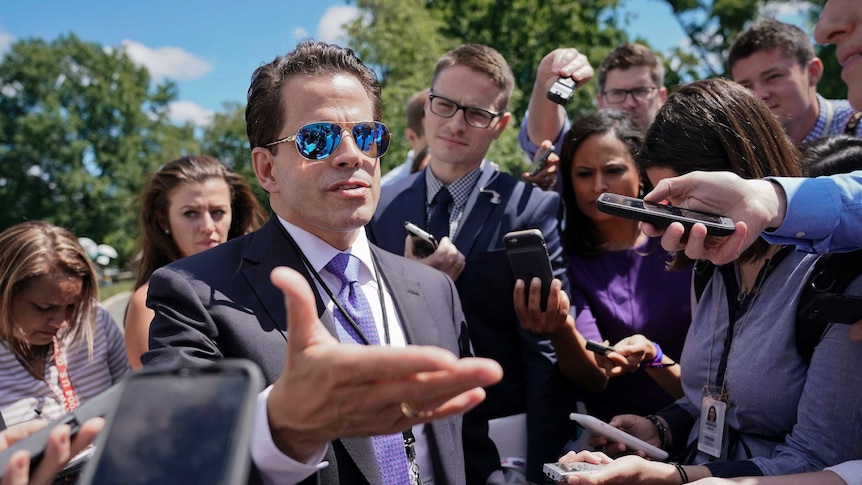 Scaramucci wears suit and blue reflective aviators as he makes his way through a press crowd