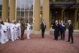 King Charles and his staff stand right, two people hold torches aflame centre, and a group of torchbearers in white left