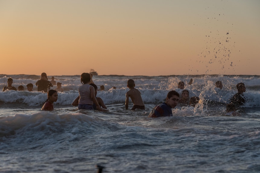 Little boys jumping in the surf at sunset 