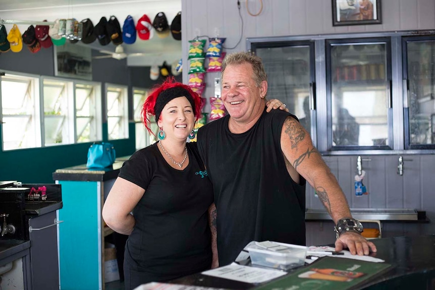 A man and woman stand beside each other behind a bar.