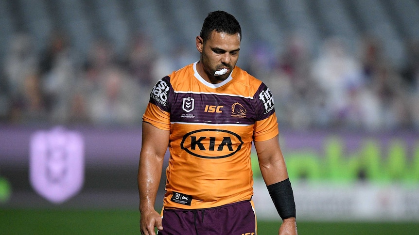 A dejected Broncos player walks off with his mouthguard out.