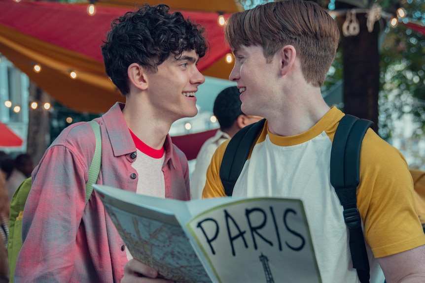 Two young men look at each other smiling while one holds a map of Paris