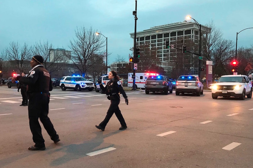 Police officers direct traffic outside a hospital, which is surrounded by emergency vehicles.