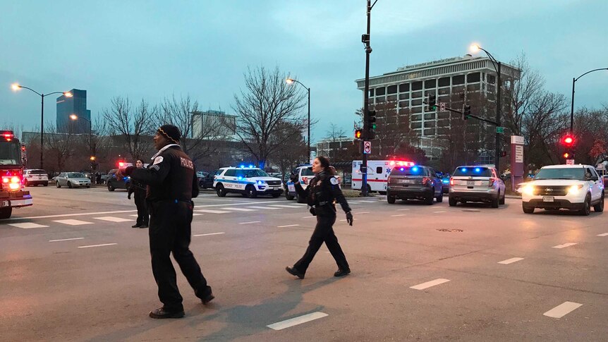 Police officers direct traffic outside a hospital, which is surrounded by emergency vehicles.
