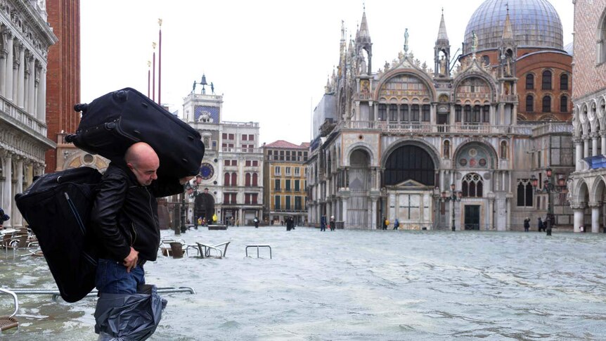 A man wades through flooded St Mark's Square in Venice