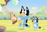 Still from Bluey episode The Sign showing three cartoon dogs in a backyard playing on a swing.
