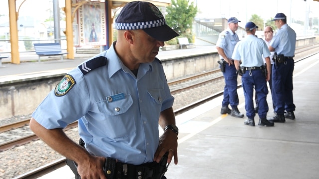 An officer with the NSW Police Transport Command speaks with a Newcastle commuter.