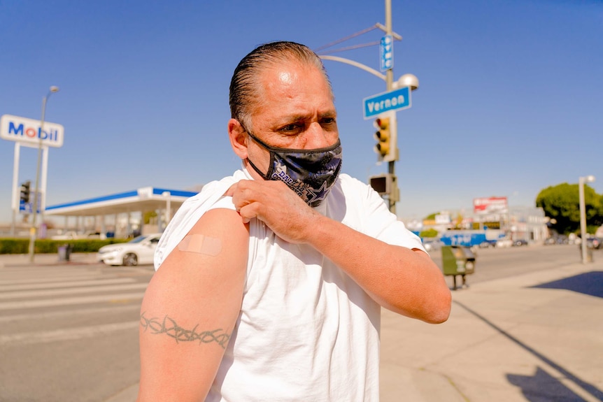 A man in a face mask and t-shirt holds