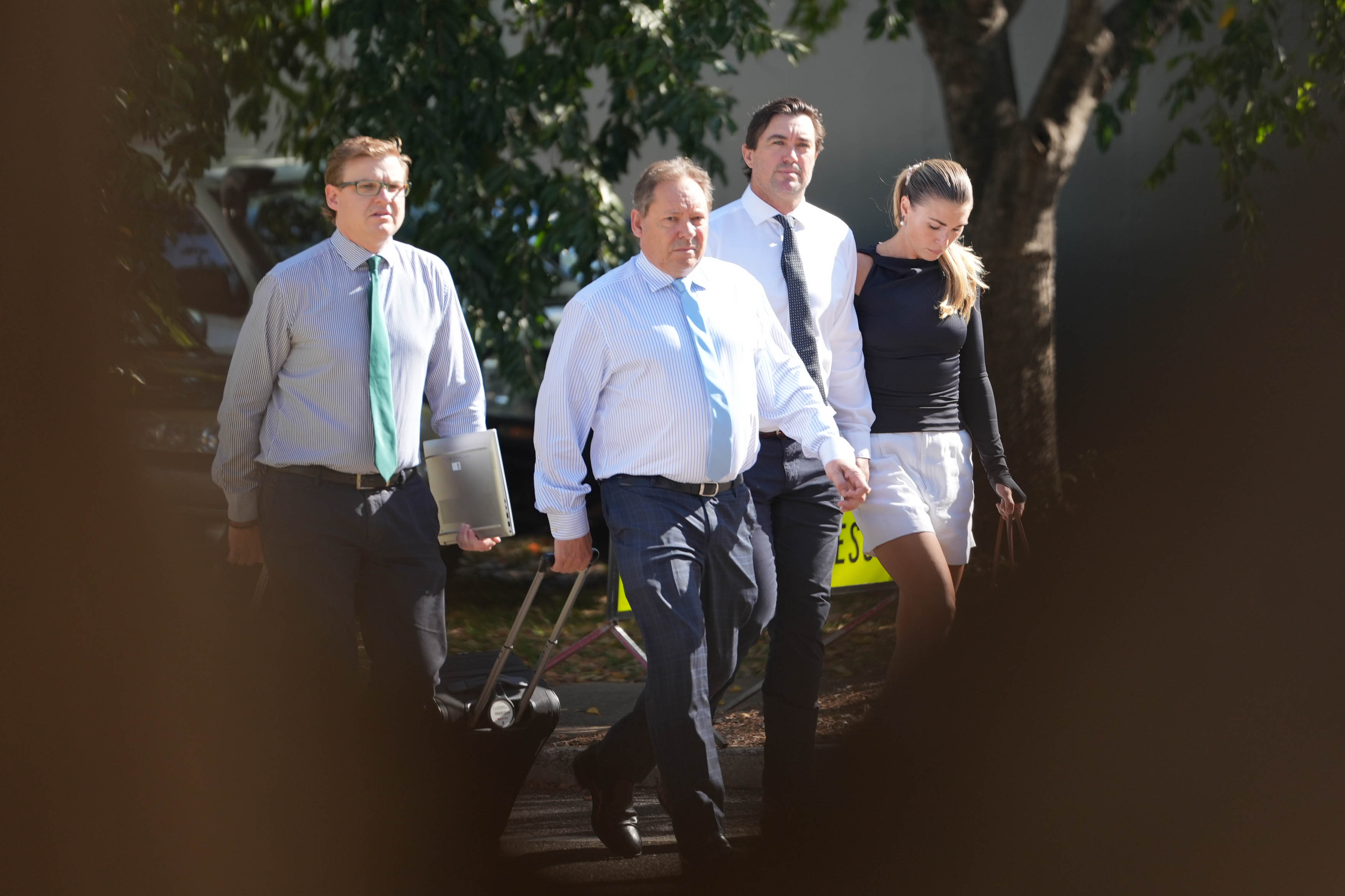 Three men and one woman walking outside.