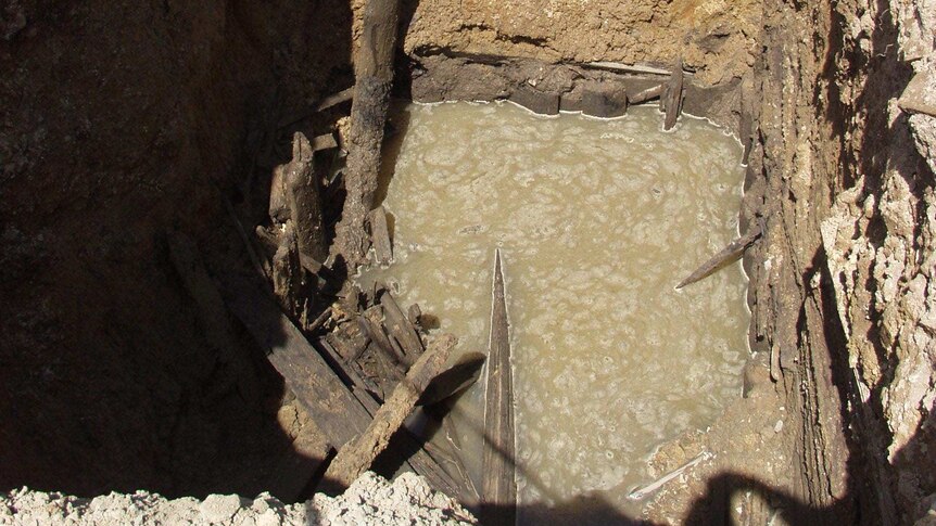 An aerial view of a caved-in mine shaft filled with water.