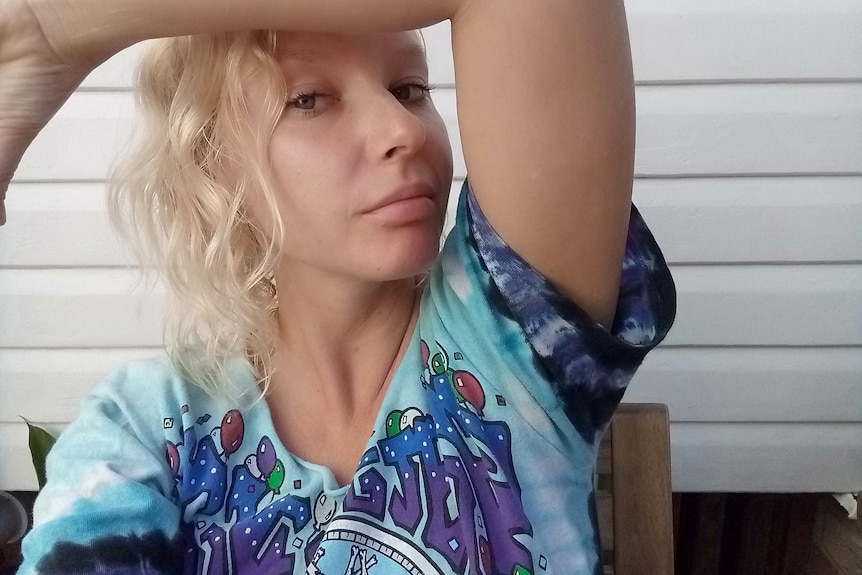A selfie of a young woman with blonde hair and a blue tie-dye shirt.