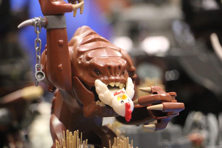 Rancor from Star Wars eating a Lego figure in a chicken suit.