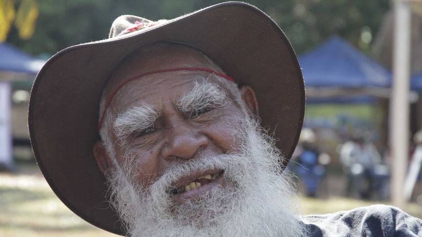 An Indigenous man with a white beard, wearing an Akubra-style hat.