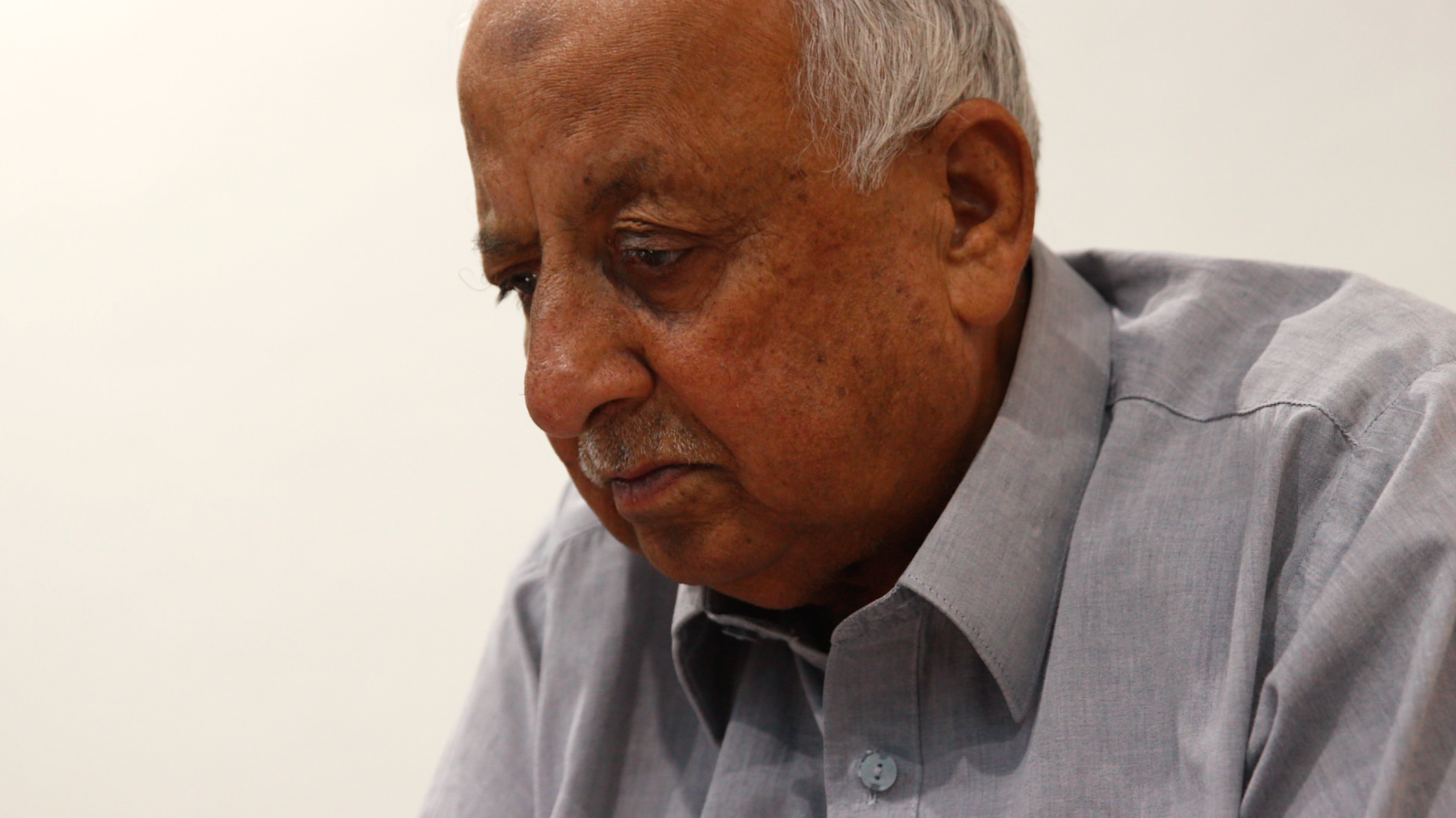 Headshot of an older man, eyes downcast.
